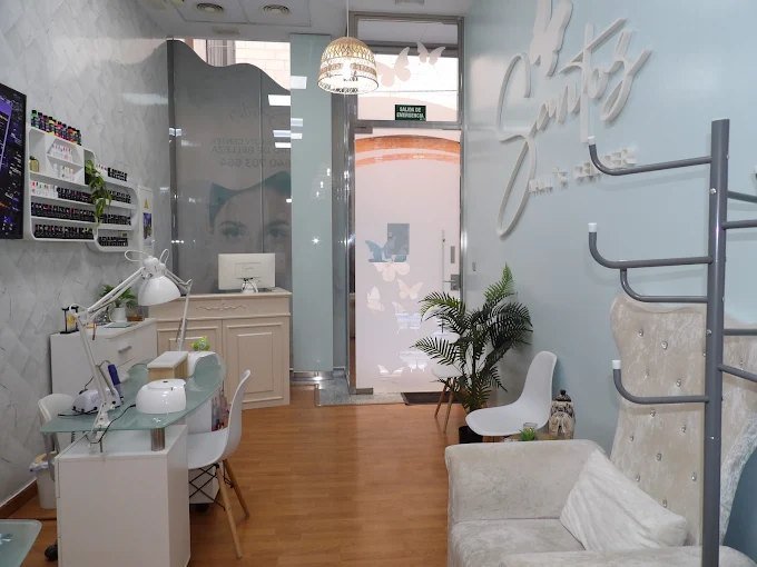Interior del salón Santos Beauty Care con mesas de manicura y el logotipo en la pared